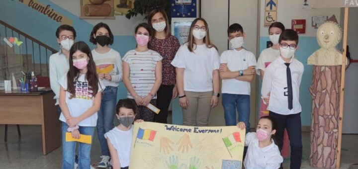 Un gruppo di alunni della scuola primaria nell'atrio della scuola mostra un cartello di benvenuto