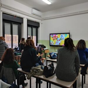 Sei docenti di scuola primaria e secondaria, seduti in una classe mentre guardano la lavagna interattiva.