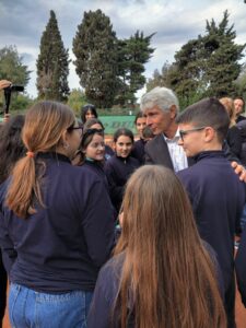 Gruppo di persone in primo piano: il Ministro dello sport al centro, stringe la mano a studenti con felpa blu