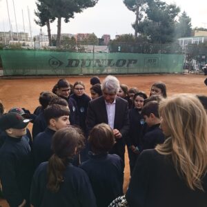 Gruppo di persone in primo piano: il Ministro dello sport al centro, stringe la mano a studenti con felpa blu